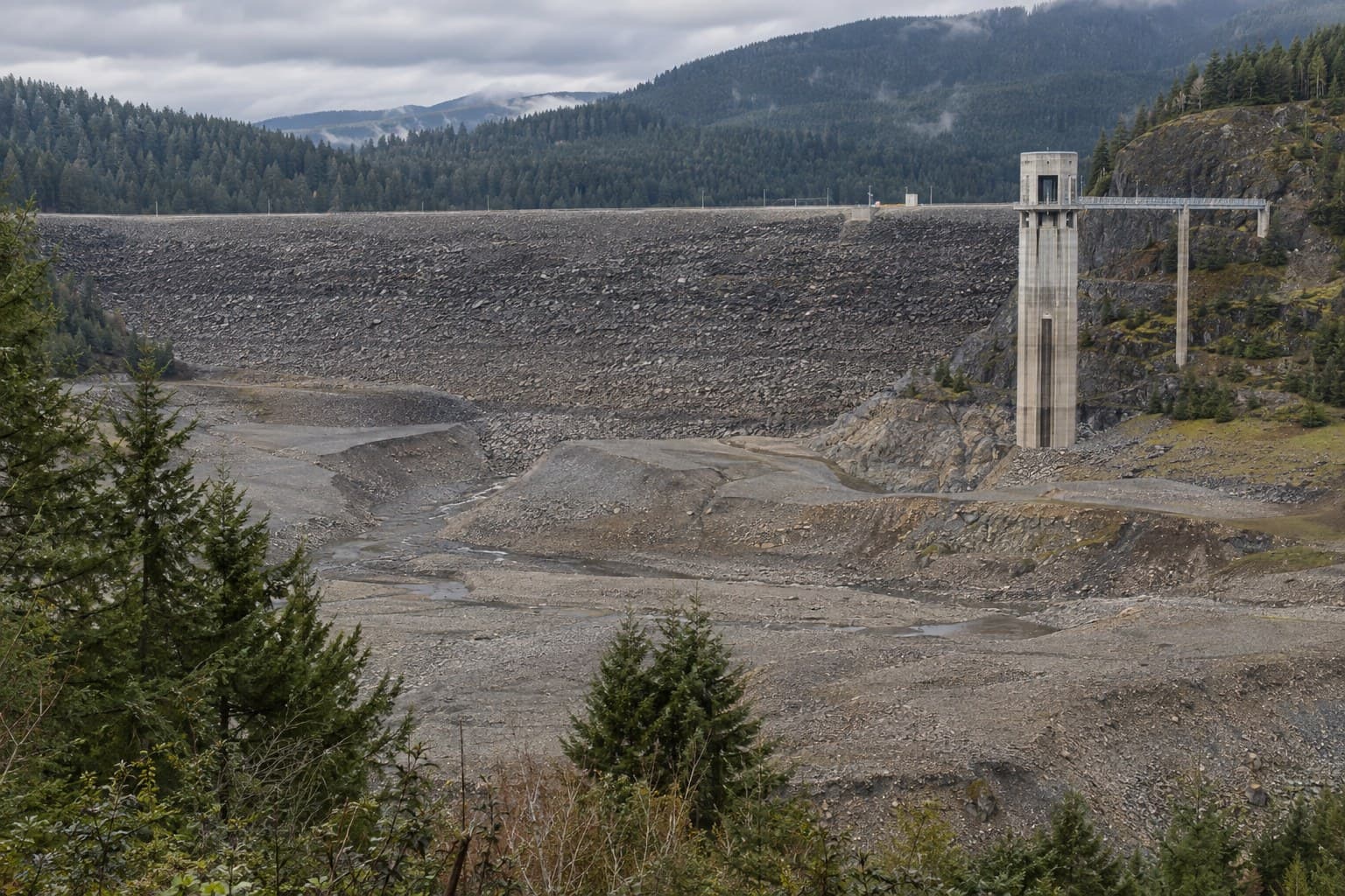 Rendering of Mud Mountain Dam's rock-fill face and intake tower seen from the Vista Trail deck above an empty reservoir