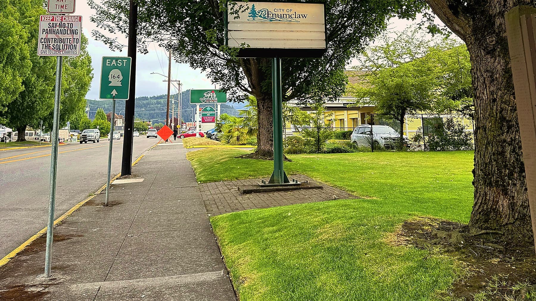The City of Enumclaw entry sign on Griffin Avenue beside a green East 164 state route shield