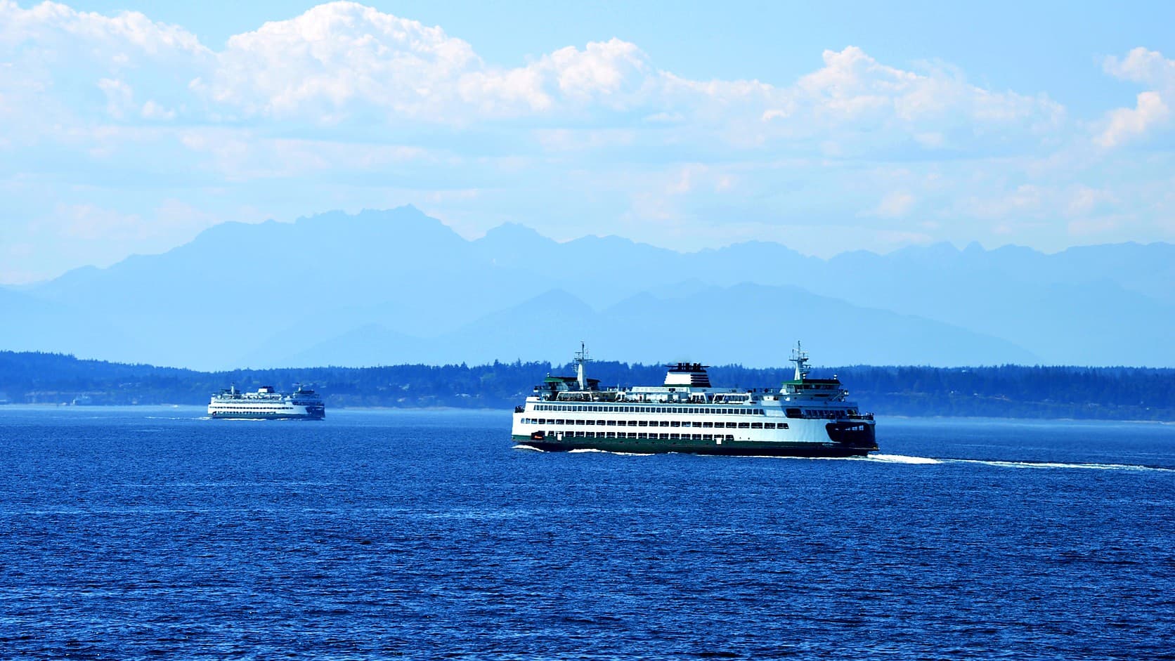 Two Washington State Ferries crossing Puget Sound with the Olympic Mountains behind them